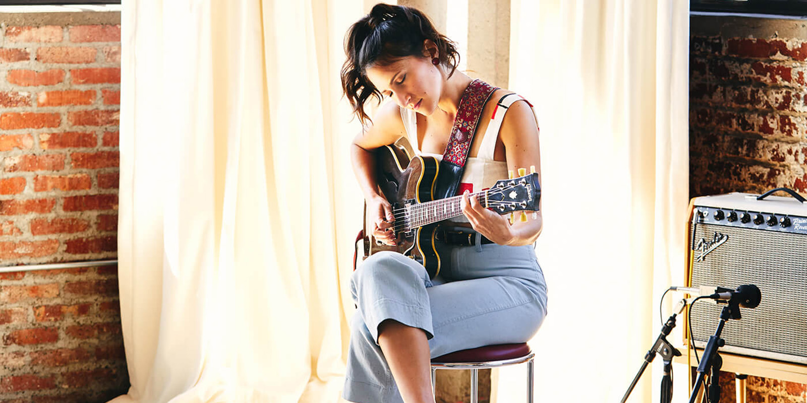 Image of a woman playing the guitar on stage